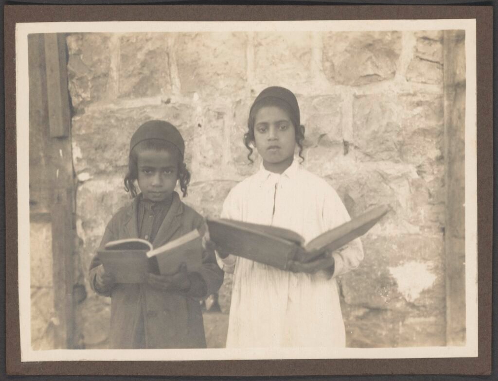 Two children reading books together in an early 1900s photograph