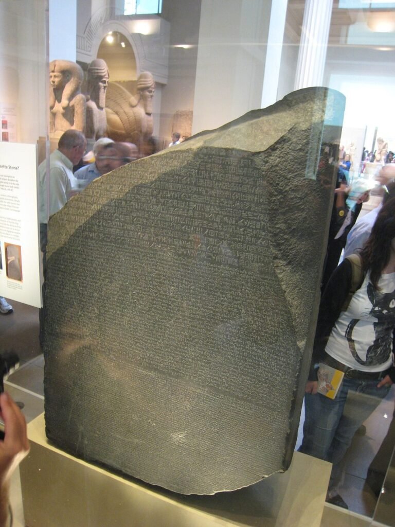 The dark gray Rosetta Stone in a glass case at the British Museum, covered in carved writing